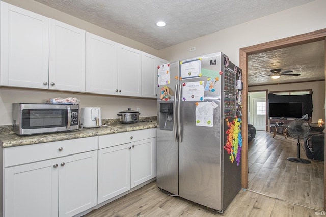 3311 Ardmore Trl, South Bend, IN 46628 - kitchen with appliances with stainless steel finishes, light wood-type flooring, a textured ceiling, white cabinets, and light stone counters