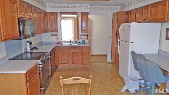 1001 Barnett St, Vincennes, IN 47591 - kitchen with electric stove, black microwave, a sink, freestanding refrigerator, and light countertops
