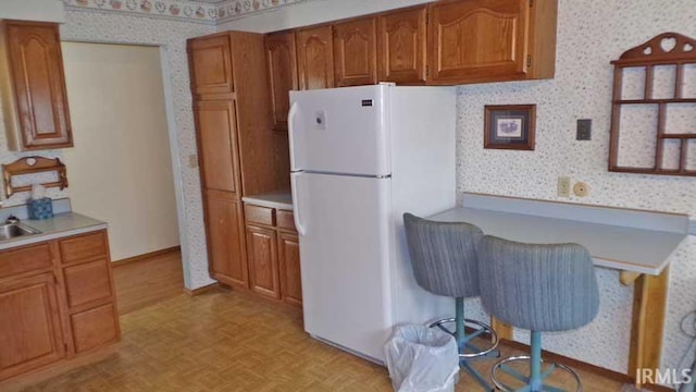 1001 Barnett St, Vincennes, IN 47591 - kitchen with freestanding refrigerator, wallpapered walls, brown cabinets, and light countertops