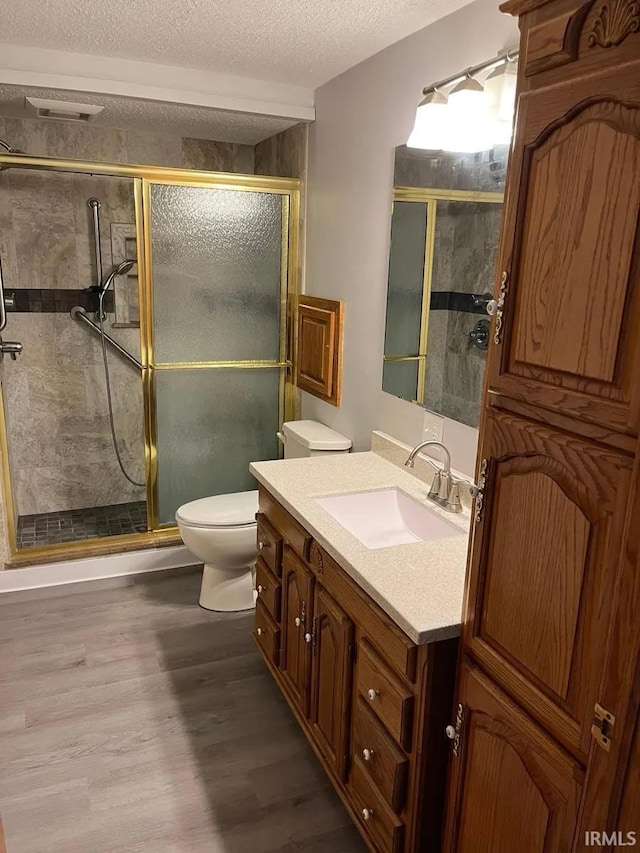 415 N Washington St, Warsaw, IN 46580 - bathroom with toilet, wood finished floors, a textured ceiling, vanity, and a shower stall