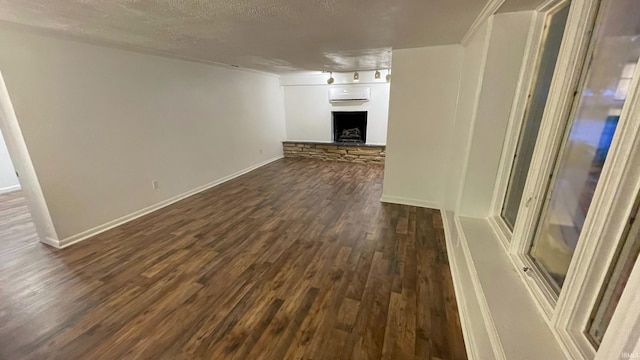 415 N Washington St, Warsaw, IN 46580 - unfurnished living room featuring dark wood-style flooring, a wall mounted AC, a fireplace, baseboards, and a textured ceiling