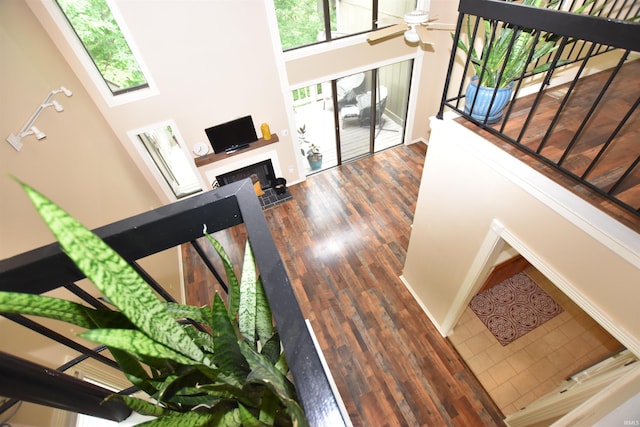 9428 S Lake Ridge Dr, Bloomington, IN 47401 - stairs featuring a fireplace, a ceiling fan, wood finished floors, a towering ceiling, and baseboards
