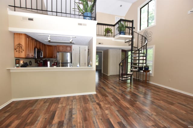 9428 S Lake Ridge Dr, Bloomington, IN 47401 - kitchen with stainless steel appliances, dark wood-type flooring, brown cabinets, a towering ceiling, and baseboards