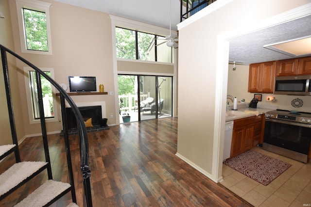 9428 S Lake Ridge Dr, Bloomington, IN 47401 - kitchen featuring appliances with stainless steel finishes, light countertops, a fireplace with raised hearth, a ceiling fan, and a sink
