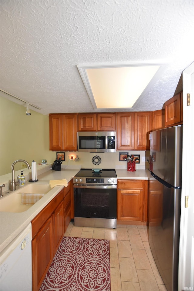 9428 S Lake Ridge Dr, Bloomington, IN 47401 - kitchen with appliances with stainless steel finishes, a textured ceiling, a sink, and light countertops