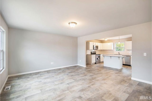 405 Somerfield Dr, Lakeville, IN 46536 - kitchen featuring appliances with stainless steel finishes, a kitchen breakfast bar, light wood-style floors, light countertops, and tasteful backsplash