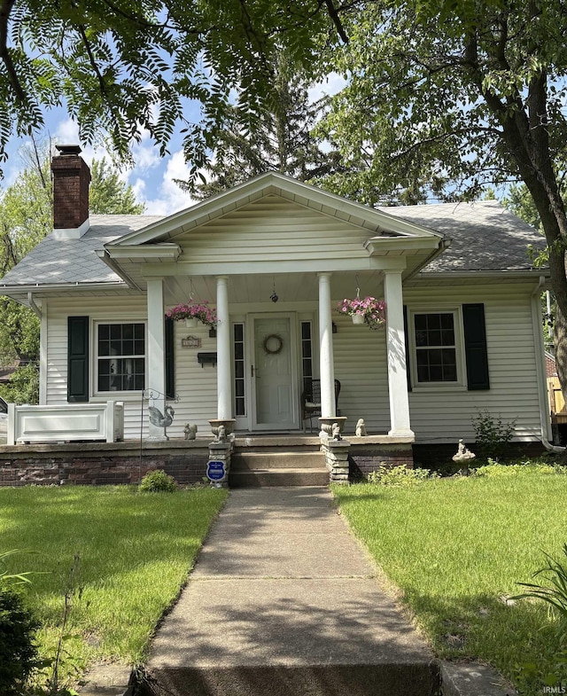 1621 Mckinley Ave, South Bend, IN 46617 - view of front of house with covered porch, a chimney, a front yard, and roof with shingles