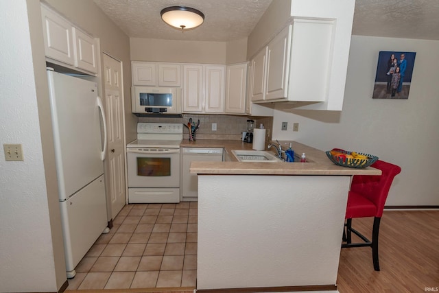 1009 Berkley Cir, Mishawaka, IN 46544 - kitchen with white appliances, a sink, a peninsula, white cabinetry, and a kitchen bar