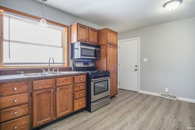 2659 Castine Walk, Mishawaka, IN 46544 - kitchen with appliances with stainless steel finishes, a sink, brown cabinetry, and light wood finished floors