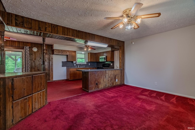 1113 E 500 S, Wabash, IN 46992 - kitchen with range, a peninsula, dark colored carpet, dark countertops, and brown cabinets