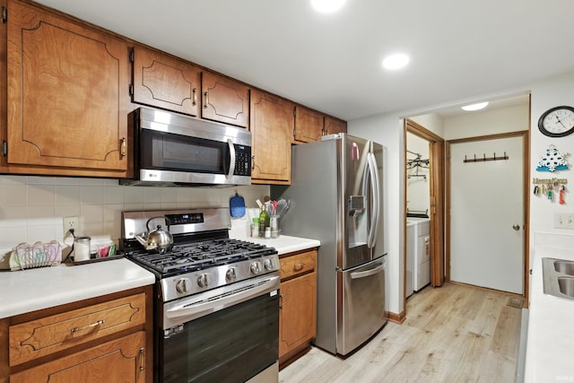 5816 Bayside Dr, Fort Wayne, IN 46815 - kitchen with appliances with stainless steel finishes, light wood-style flooring, washer / dryer, decorative backsplash, and brown cabinets