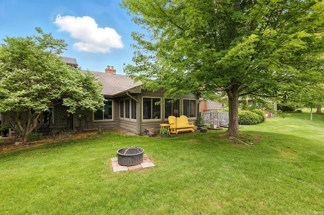 5816 Bayside Dr, Fort Wayne, IN 46815 - rear view of house with a fire pit, a chimney, a shingled roof, a yard, and a sunroom