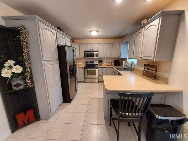 1749 W 1st St, Jasper, IN 47546 - kitchen featuring appliances with stainless steel finishes, a peninsula, light tile patterned flooring, light countertops, and a sink