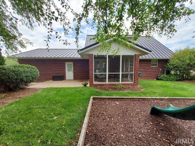 1749 W 1st St, Jasper, IN 47546 - rear view of house featuring a standing seam roof, brick siding, a patio area, and a yard