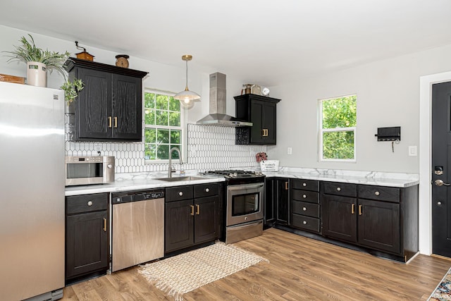 501 Spring Beach Rd, Rome City, IN 46784 - kitchen featuring stainless steel appliances, wall chimney exhaust hood, a sink, tasteful backsplash, and light wood-style floors