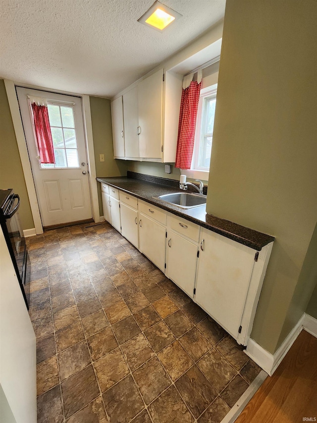 206 S Van Buren St, Monroe, IN 46772 - kitchen with a sink, dark countertops, baseboards, a textured ceiling, and white cabinetry