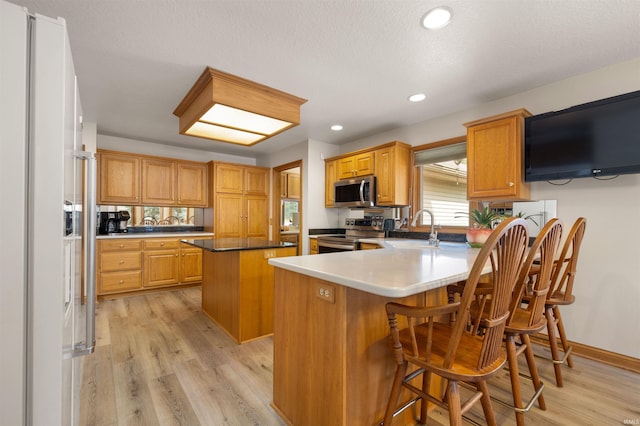 6615 Cherry Hill Pkwy, Fort Wayne, IN 46835 - kitchen featuring appliances with stainless steel finishes, a sink, a peninsula, light wood-style floors, and a center island