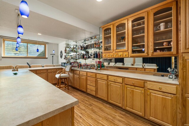 6615 Cherry Hill Pkwy, Fort Wayne, IN 46835 - kitchen featuring light wood-type flooring, light countertops, a peninsula, glass insert cabinets, and brown cabinetry