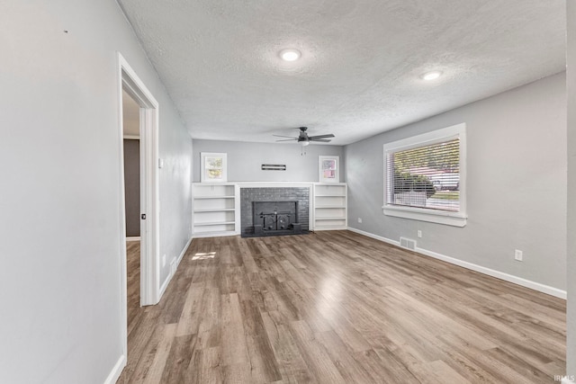 340 W Turner St, Bloomfield, IN 47424 - unfurnished living room featuring ceiling fan, a textured ceiling, baseboards, wood finished floors, and a fireplace with flush hearth