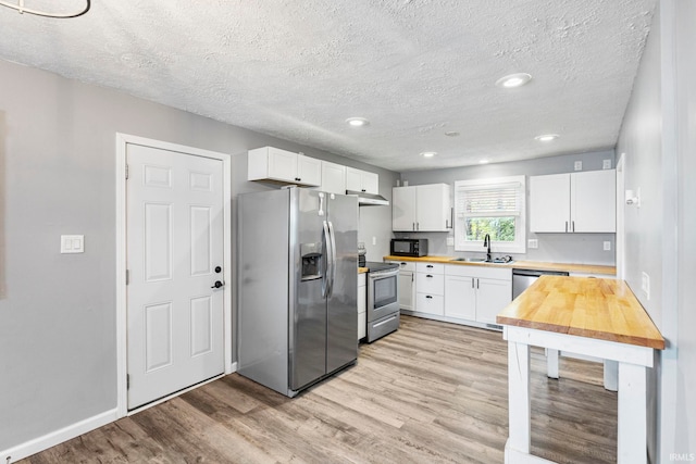 340 W Turner St, Bloomfield, IN 47424 - kitchen featuring stainless steel appliances, a sink, light wood-style floors, white cabinetry, and butcher block countertops