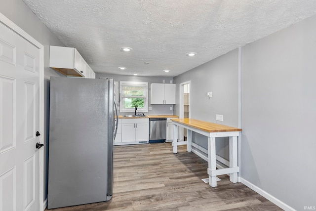 340 W Turner St, Bloomfield, IN 47424 - kitchen with stainless steel appliances, light wood finished floors, a textured ceiling, white cabinetry, and recessed lighting