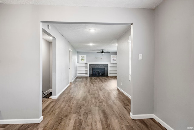 340 W Turner St, Bloomfield, IN 47424 - unfurnished living room with wood finished floors, baseboards, a fireplace, a ceiling fan, and a textured ceiling