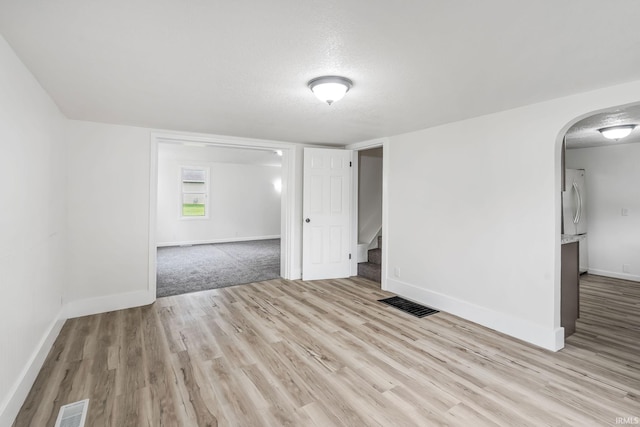 503 Graceland Ave, Claypool, IN 46510 - empty room featuring stairway, baseboards, arched walkways, wood finished floors, and a textured ceiling