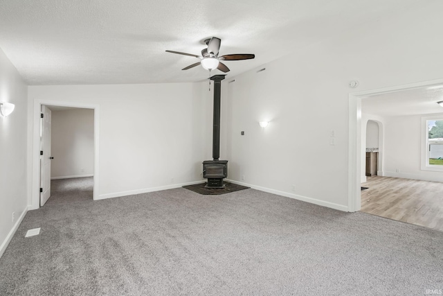 503 Graceland Ave, Claypool, IN 46510 - unfurnished living room with a wood stove, carpet floors, ceiling fan, baseboards, and arched walkways