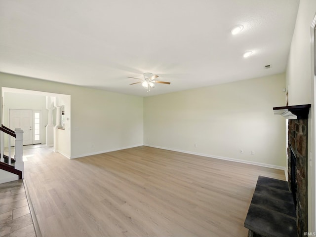 13395 Synch Ct, Fort Wayne, IN 46814 - unfurnished living room featuring a ceiling fan, a fireplace, baseboards, light wood finished floors, and stairway