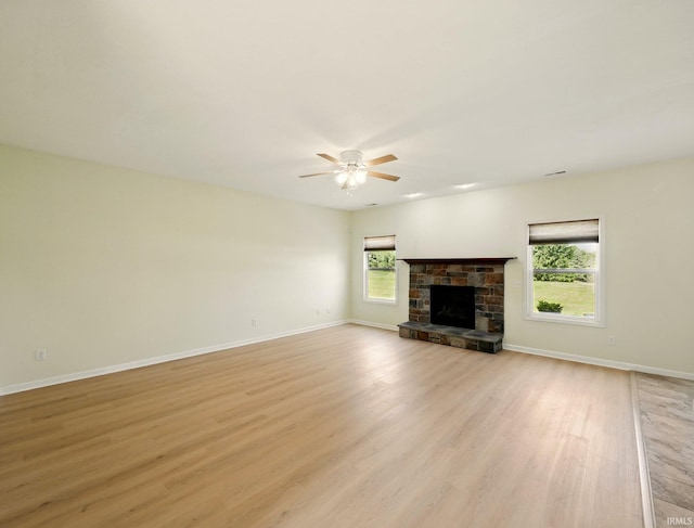 13395 Synch Ct, Fort Wayne, IN 46814 - unfurnished living room with ceiling fan, light wood finished floors, a stone fireplace, and baseboards