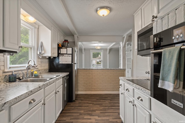 2527 Woodmont Dr, South Bend, IN 46614 - kitchen featuring stainless steel appliances, a sink, dark wood-type flooring, white cabinetry, and brick wall
