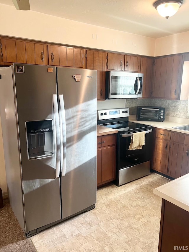 416 Hopkins Rd, Indianapolis, IN 46229 - kitchen with appliances with stainless steel finishes, light countertops, brown cabinetry, tasteful backsplash, and a sink