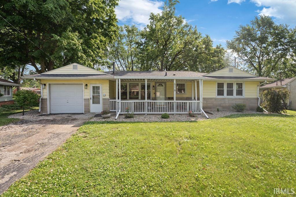 516 Holly Ln, Kokomo, IN 46902 - ranch-style home with covered porch, driveway, a garage, a front yard, and stone siding