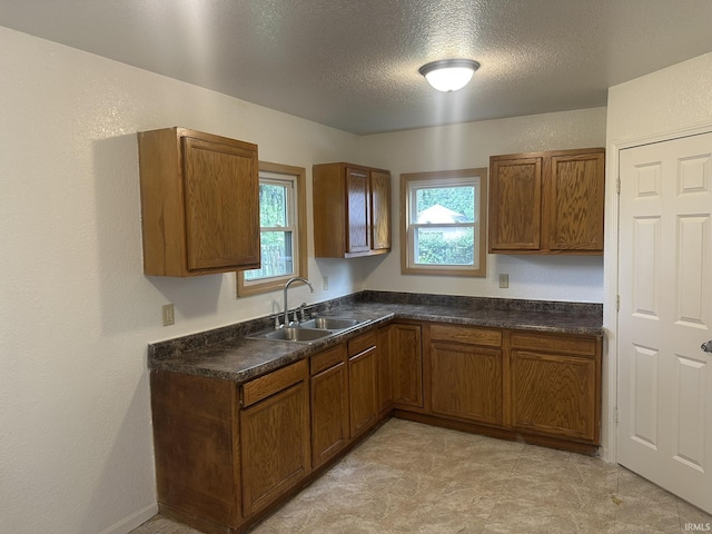 3324 Alexander St, Fort Wayne, IN 46806 - kitchen with a sink, brown cabinetry, dark countertops, plenty of natural light, and a textured ceiling