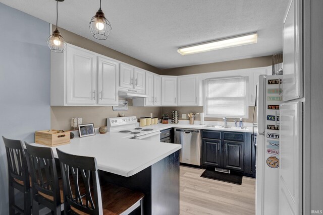 9617 S Lake Ridge Dr Unit 4, Bloomington, IN 47401 - kitchen featuring white appliances, under cabinet range hood, a peninsula, a sink, and light wood-type flooring