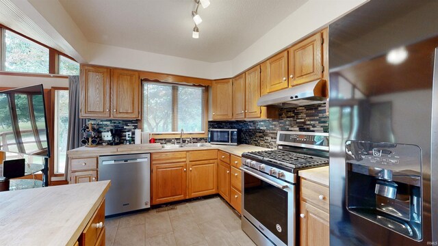 7333 W Newton Stewart Rd, Taswell, IN 47175 - kitchen with stainless steel appliances, under cabinet range hood, light countertops, a sink, and decorative backsplash
