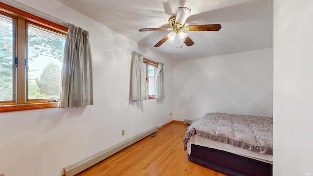 7333 W Newton Stewart Rd, Taswell, IN 47175 - bedroom with a baseboard heating unit, light wood-style flooring, baseboard heating, ceiling fan, and baseboards