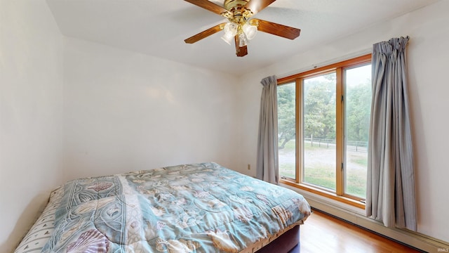 7333 W Newton Stewart Rd, Taswell, IN 47175 - bedroom with multiple windows, a baseboard heating unit, a ceiling fan, and light wood-type flooring