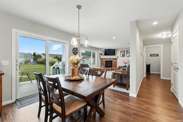 1308 Hideaway Dr, Auburn, IN 46706 - dining room featuring a brick fireplace, light wood-style flooring, recessed lighting, a chandelier, and baseboards