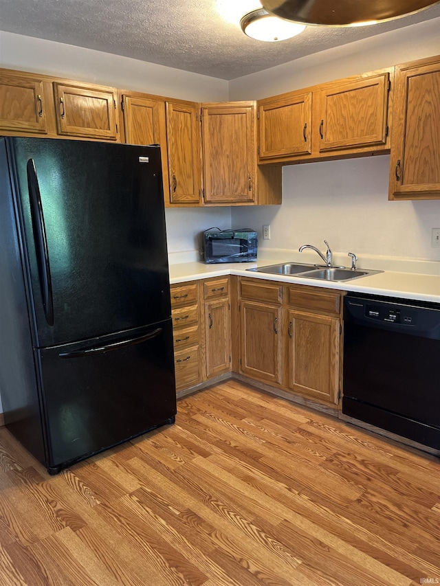 336 Wilmington Ct Unit C, Bloomington, IN 47401 - kitchen featuring black appliances, a sink, light countertops, light wood-style floors, and brown cabinets