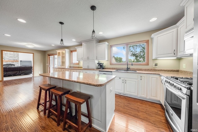 521 Glenmoor Dr, Fort Wayne, IN 46804 - kitchen featuring gas range, a sink, a center island, a breakfast bar area, and white cabinets