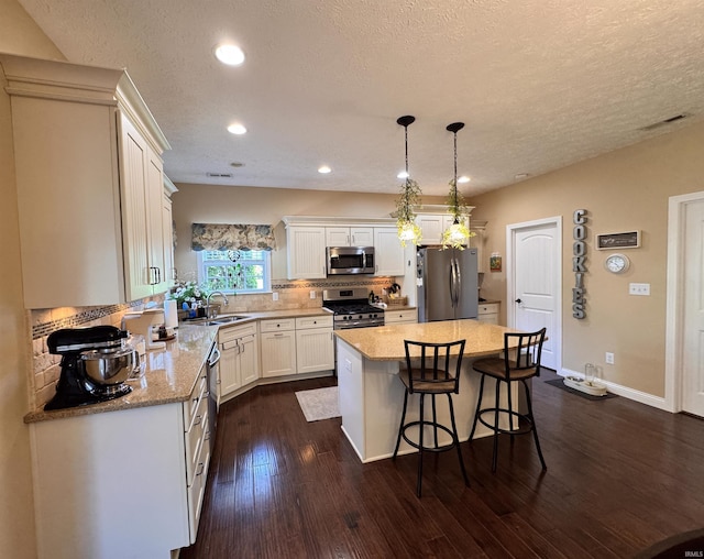 4691 Flagship Ln, Lafayette, IN 47909 - kitchen featuring appliances with stainless steel finishes, dark wood finished floors, a kitchen island, decorative backsplash, and white cabinets