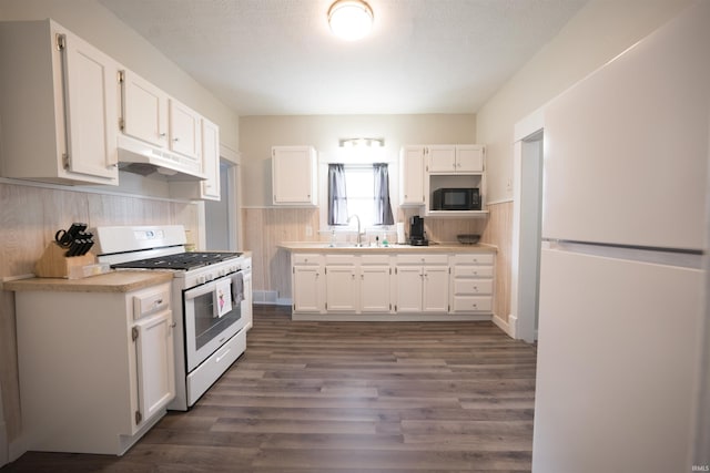 1014 W 7th St, Mishawaka, IN 46544 - kitchen featuring white appliances, under cabinet range hood, white cabinets, a wainscoted wall, and a sink