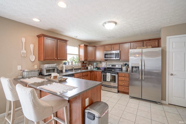 460 Kettle Cir, Lafayette, IN 47905 - kitchen featuring appliances with stainless steel finishes, a peninsula, dark countertops, brown cabinetry, and a kitchen breakfast bar