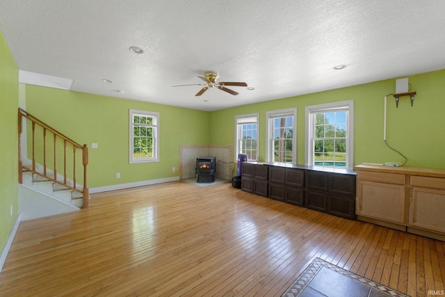 2890 W 400 N, Columbia City, IN 46725 - unfurnished living room featuring ceiling fan, light wood finished floors, stairway, a wood stove, and a textured ceiling