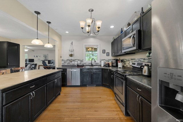 2890 W 400 N, Columbia City, IN 46725 - kitchen with stainless steel appliances, dark cabinetry, dark countertops, light wood-style floors, and decorative light fixtures