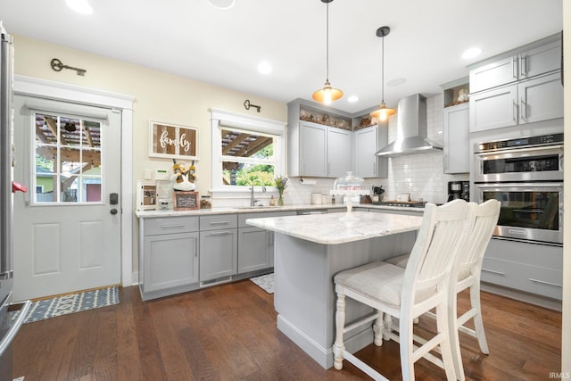 1214 W Jefferson Blvd, Fort Wayne, IN 46802 - kitchen with wall chimney range hood, gray cabinets, double oven, dark wood finished floors, and backsplash