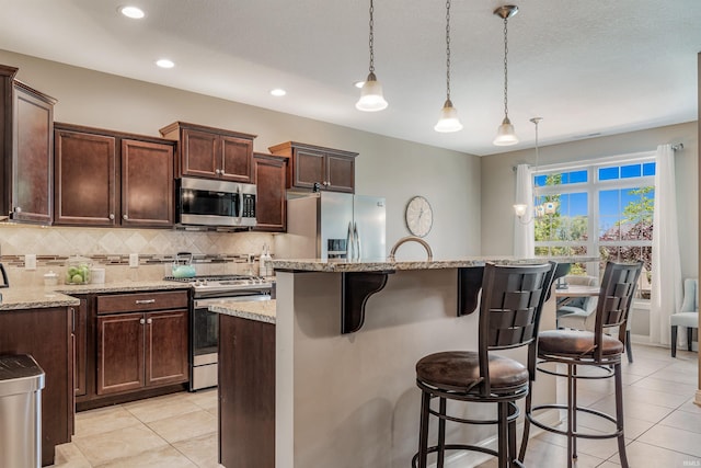 319 Pistoia Cv, Fort Wayne, IN 46845 - kitchen featuring appliances with stainless steel finishes, decorative backsplash, light tile patterned floors, a breakfast bar area, and a center island with sink