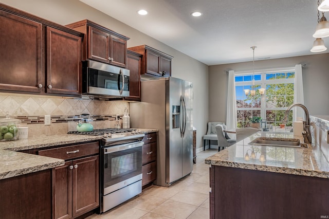 319 Pistoia Cv, Fort Wayne, IN 46845 - kitchen featuring stainless steel appliances, decorative backsplash, light stone counters, light tile patterned floors, and hanging light fixtures