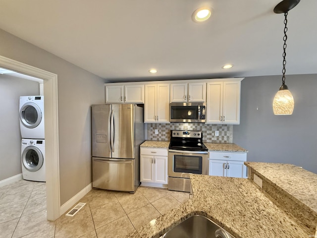 9820 Arbor Lake Dr, Newburgh, IN 47630 - kitchen with appliances with stainless steel finishes, estacked washer and dryer, white cabinets, backsplash, and recessed lighting